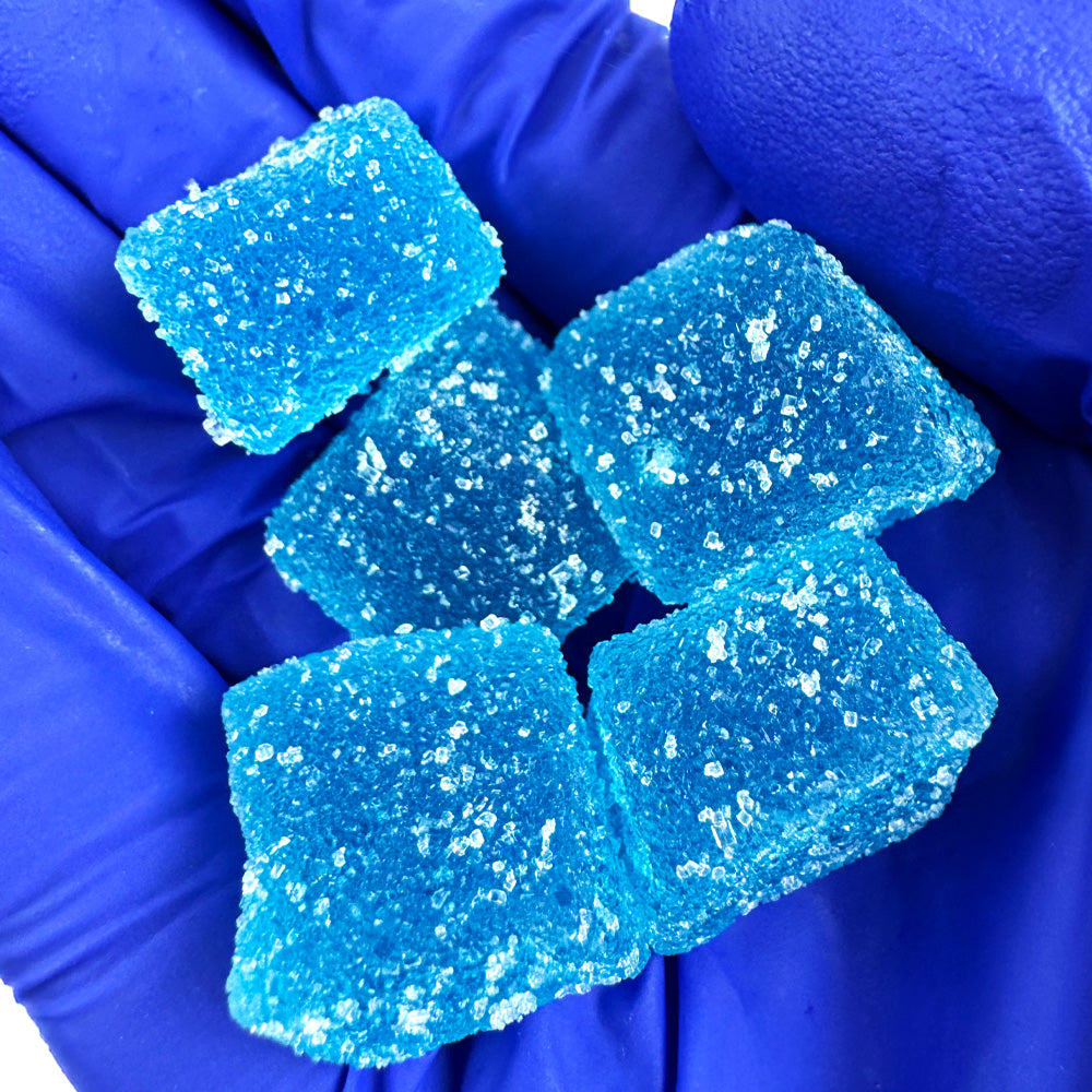 Main qui tient plusieurs gummies au THC bleus